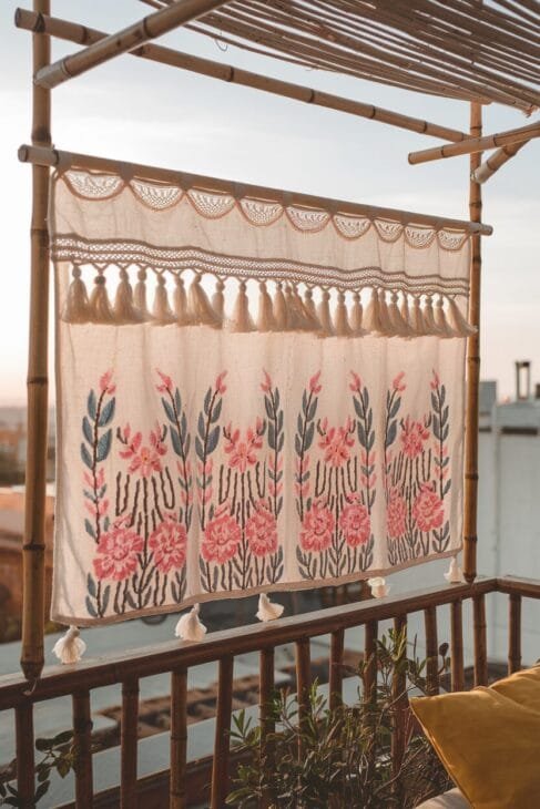 Boho Balkon Sichtschutz mit bestickten Stoffen und Bambus.