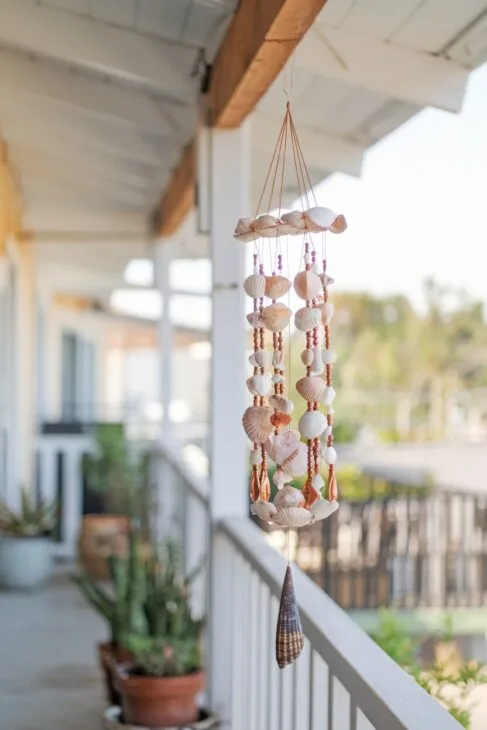 DIY Windspiel aus Muscheln und Perlen auf einem Boho Balkon.