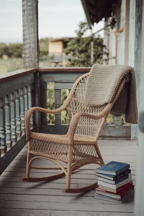 Schaukelstuhl auf einem Boho Balkon mit kuscheligen Decken.